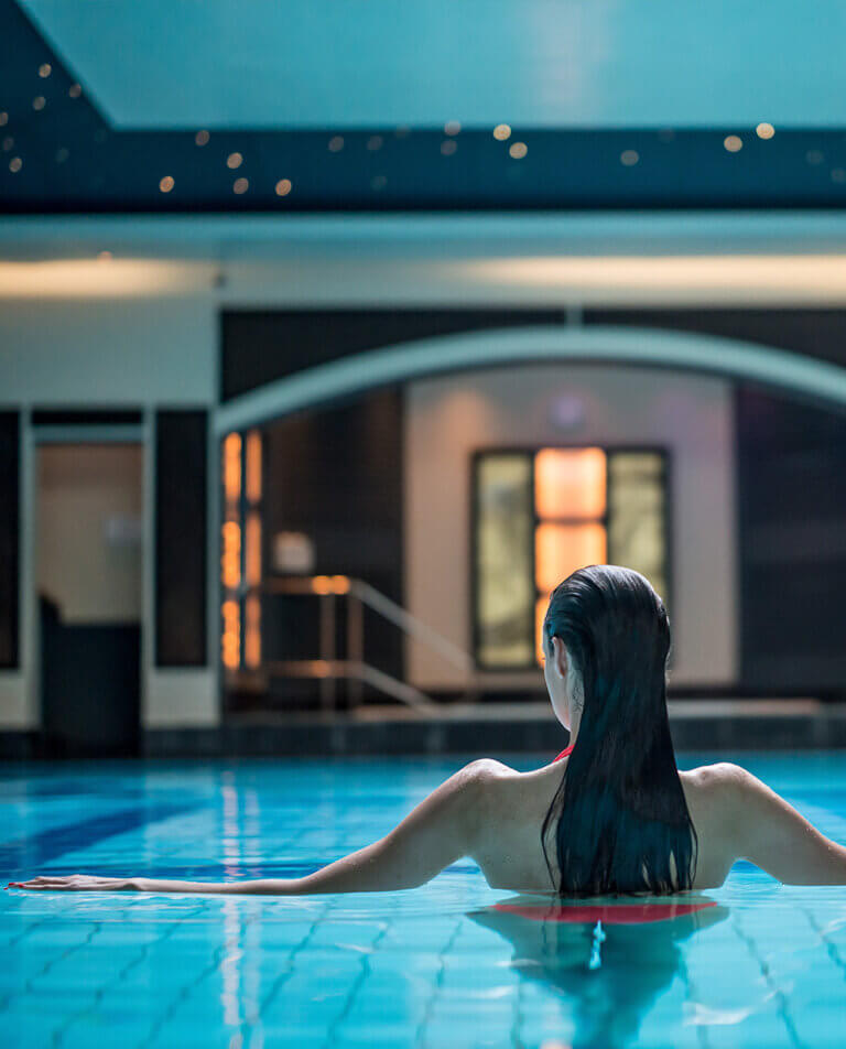 Woman enjoys night time swim in lit up pool at Careys Manor Hotel & SenSpa