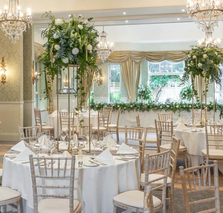 Room set up for wedding breakfast at Careys Manor Hotel with green foliage and white floral decor