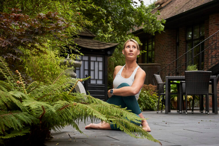 Woman in stretching pose in the courtyard at Zen Garden restaurant, surrounded by trees