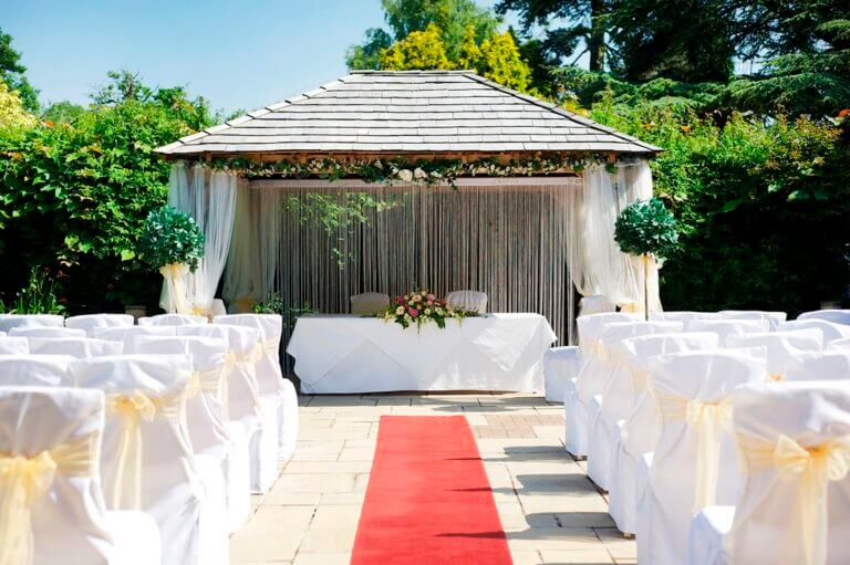 Summer day wedding ceremony set up outdoors with red carpet 