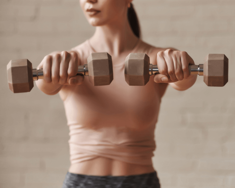 Woman holds two small dumbbells up in front of her in Iron Yoga class