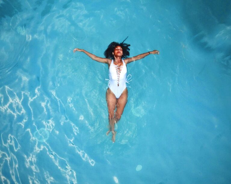 Woman in white swimsuit floats in relaxing blue swimming pool