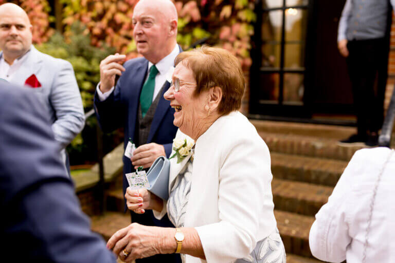 Wedding guest laughs happily on wedding day in the grounds of Careys Manor hotel in autumn