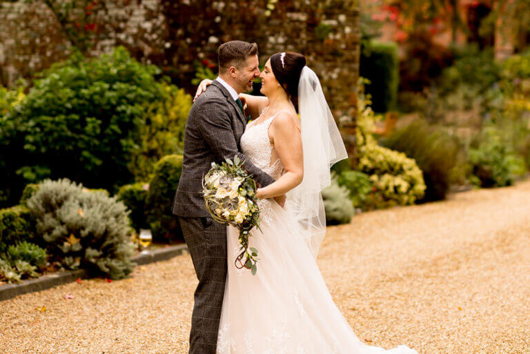 Bride and groom look lovingly at each other in wedding photo taken outdoors at Careys Manor hotel on colourful autumn day
