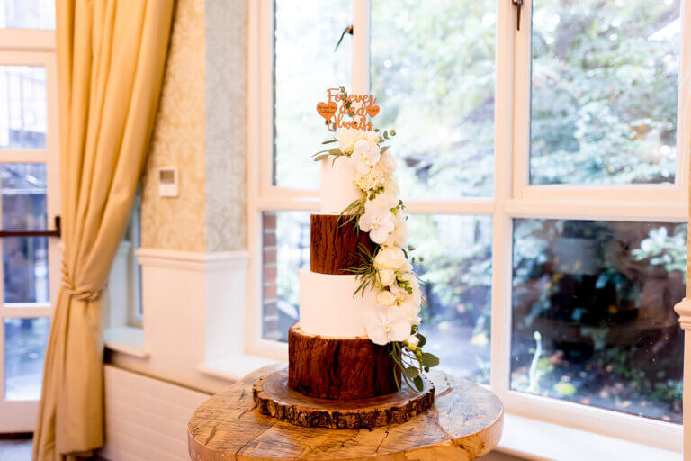 Four tier wedding cake with white flowers at Careys Manor hotel wedding venue