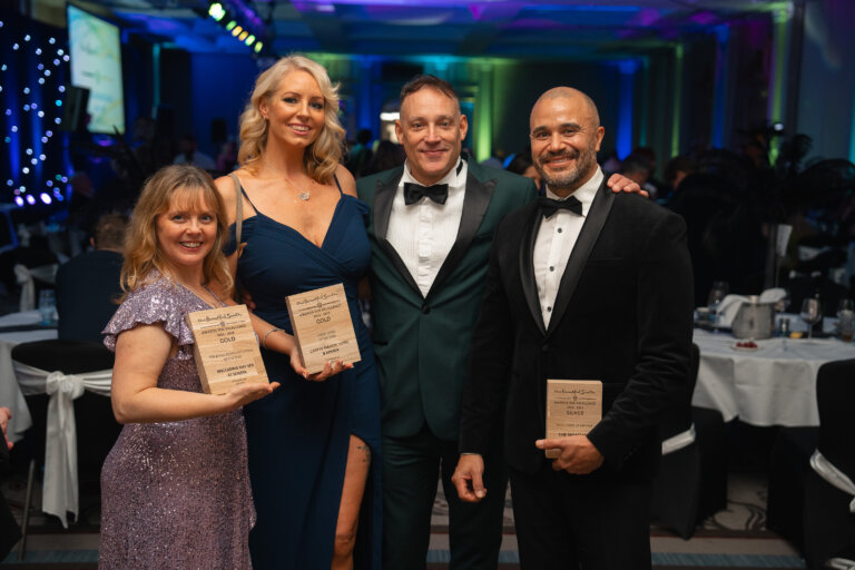Smiling hotel team members with presenter Toby Anstis holding awards